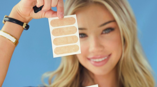 A beautiful woman holds up a small sheet of four Lunar Mouth Tape strips